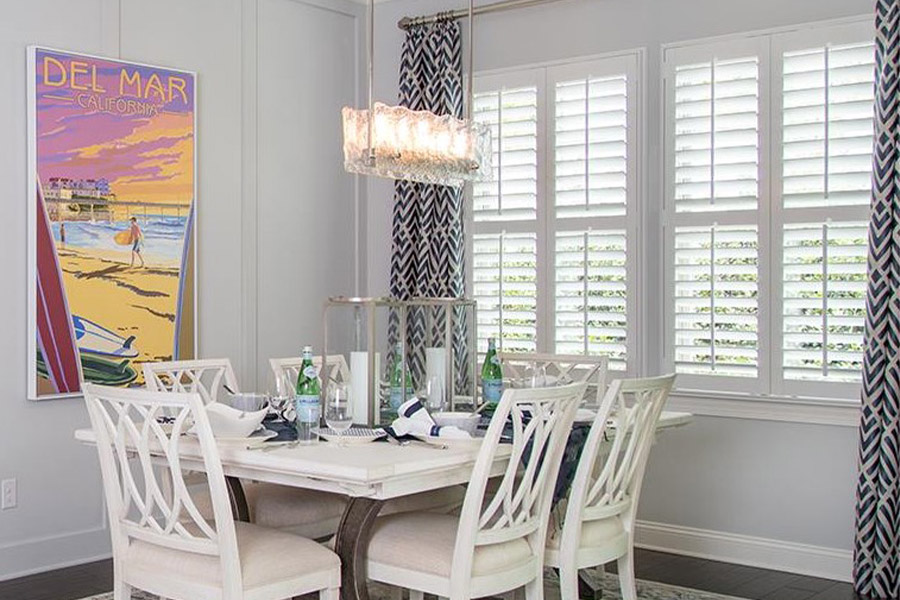White polywood shutters in a dining room with a coastal view