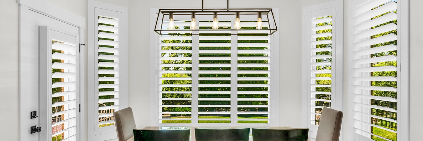  White plantation shutters in dining room with views outside