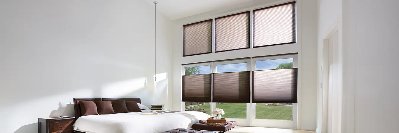 Brown cellular shades on two rows of bedroom windows, with top-down/bottom-up shades partially lowered from the top on the bottom row