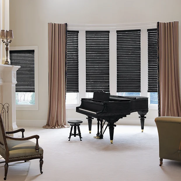 Dark brown blinds in a bow window behind a black piano