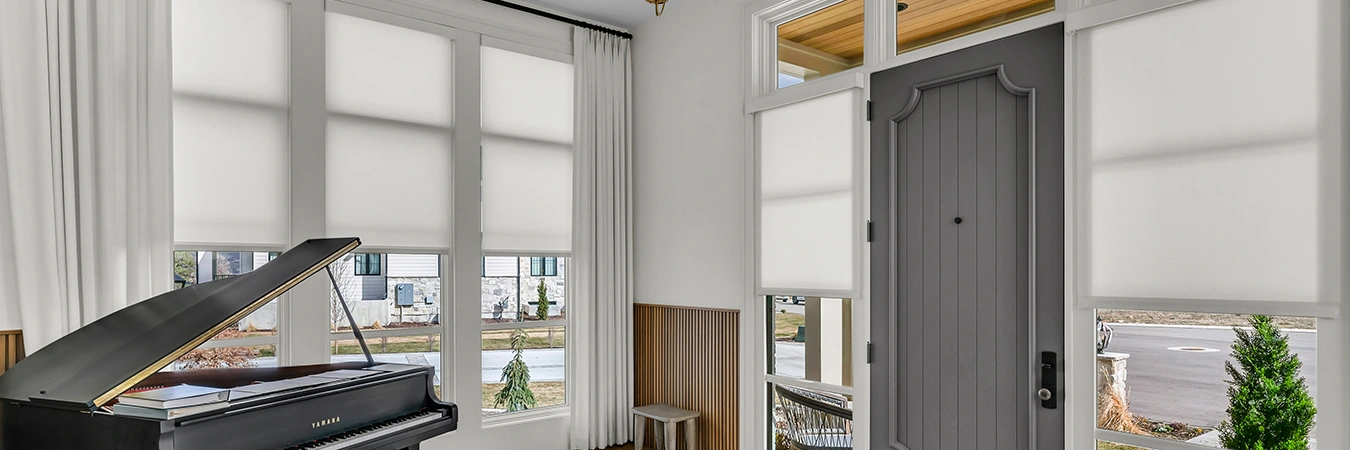 White window shades and drapes on windows in a room with a piano