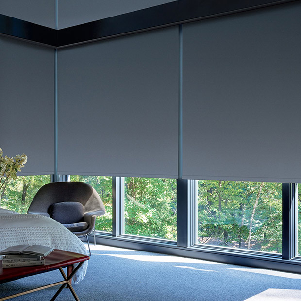 Dark gray motorized shades on tall windows in a bedroom