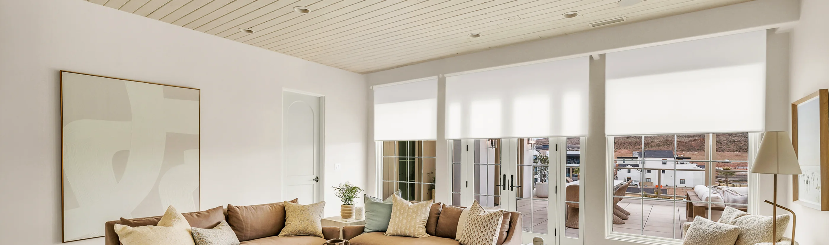 white roller shades in three large windows in a living room area