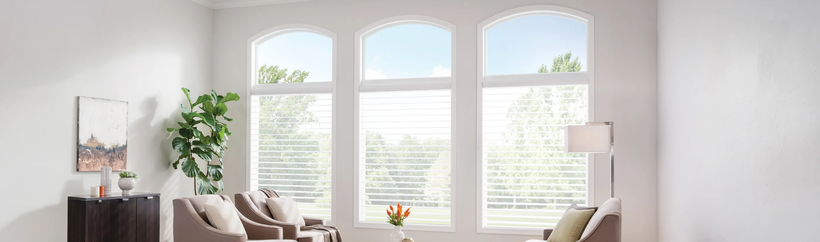 white sheer shades on on three tall windows in a white well lit living room