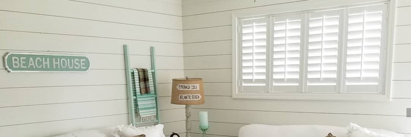 Cozy living room with shiplap and white Polywood shutters above a couch.