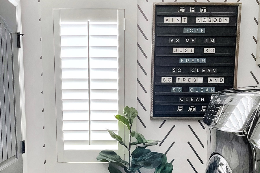 White polywood shutters inside a black and white laundry room