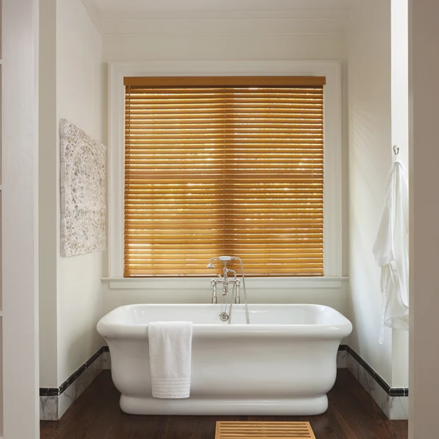 Light wood blinds above a soaking white tub