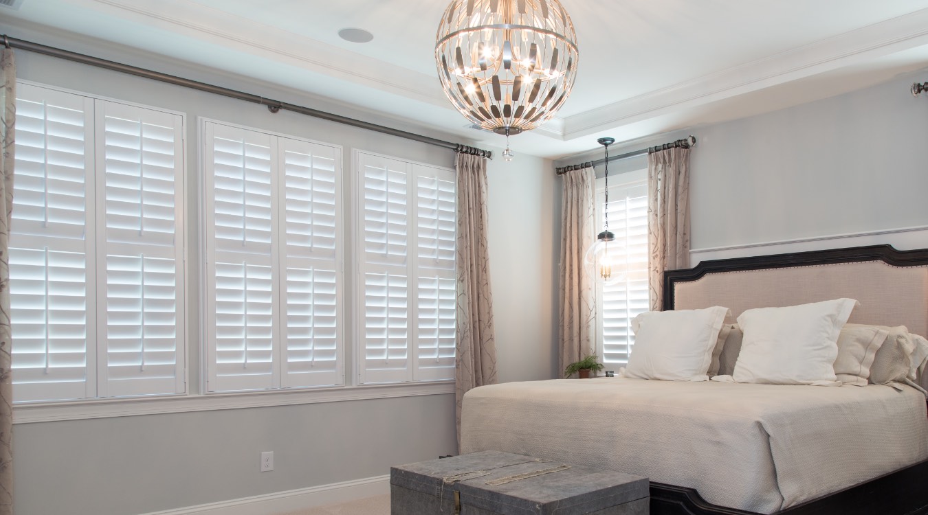 Plantation shutters and drapes in a bedroom