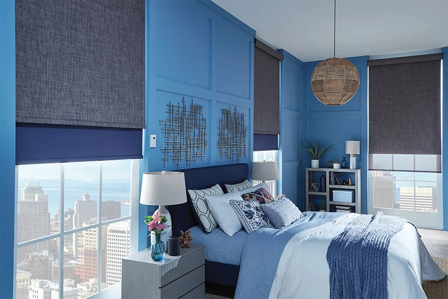 Ask your window treatment installer what type of motorized window shades will work best in your bedroom. Gray and blue motorized shades on windows in a blue bedroom