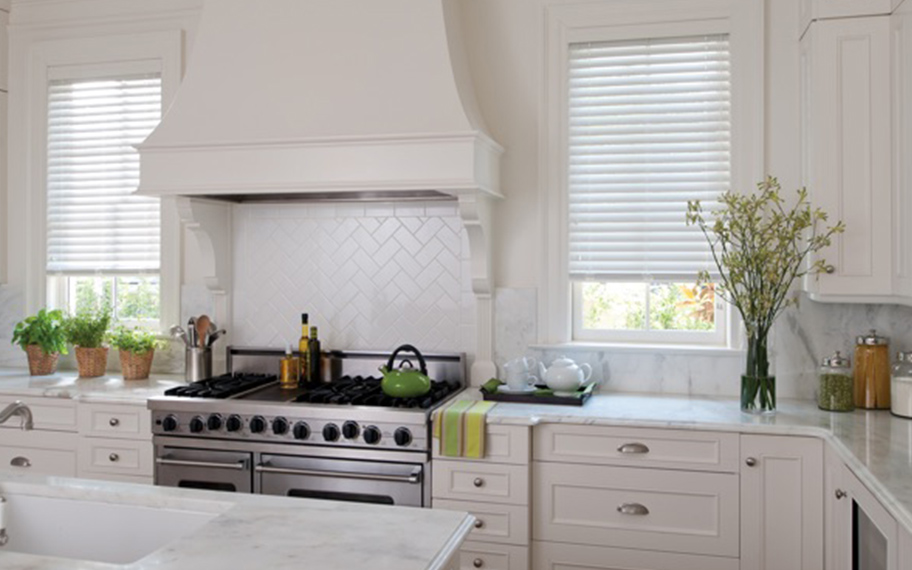 Polywood faux-wood blinds resist moisture in kitchens and bathrooms. White faux-wood blinds in a kitchen.