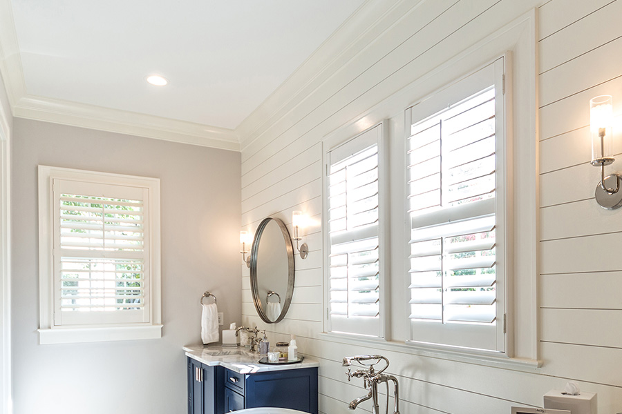 White craftsman style bathroom with two polywood shutter windows.