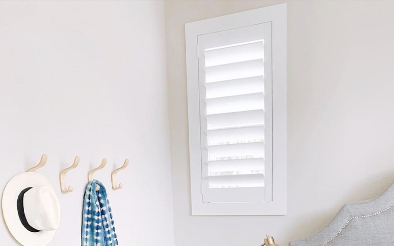 Keep your bedroom elegant and cozy with white Polywood shutters. photo credit: Audrey Crisp Interiors White polywood shutters by a bed.
