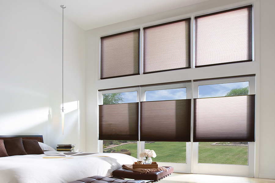 rown cellular shades on a tall wall of windows within a bedroom.