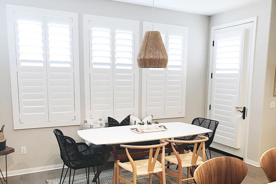 White Polywood shutters on a French door in a dining room.