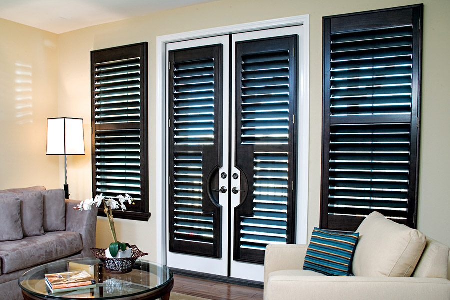 Dark brown Ovation shutters on double French doors within a living room area.