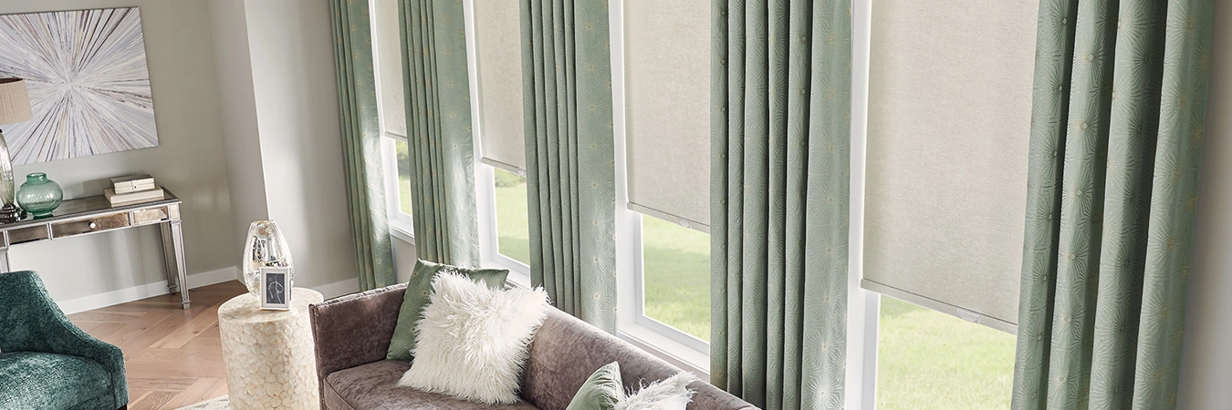sage green draperies overlaying beige roller shades in a large living room