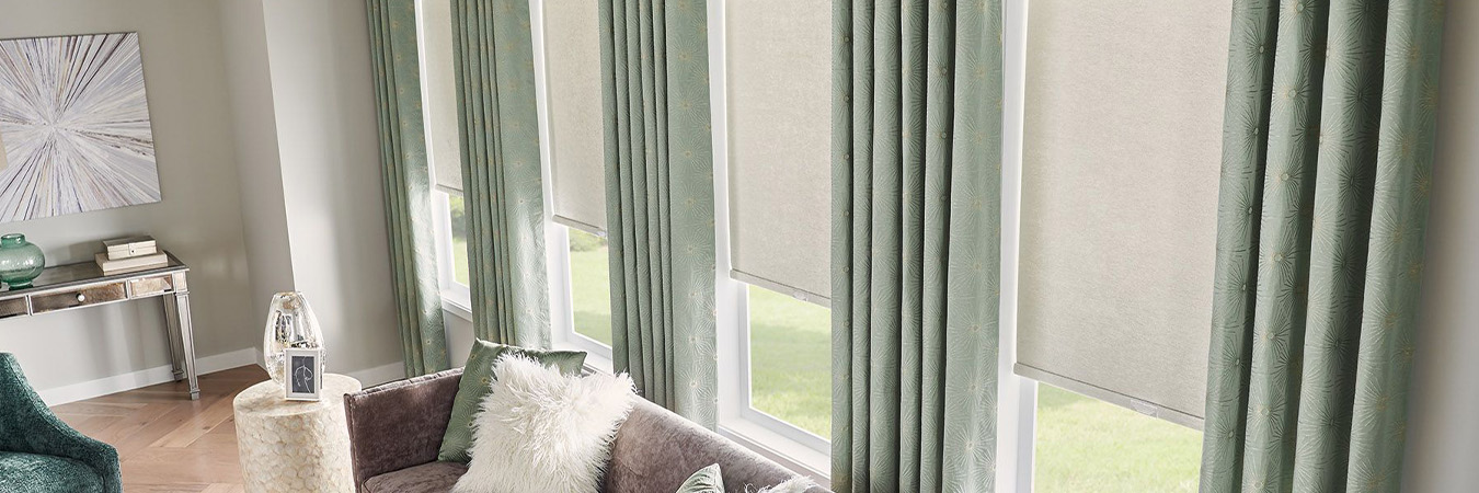 Light gray roller shades paired with green curtains in a living room