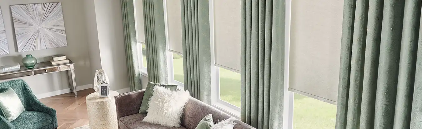 sage green draperies overlaying beige roller shades in a large living room