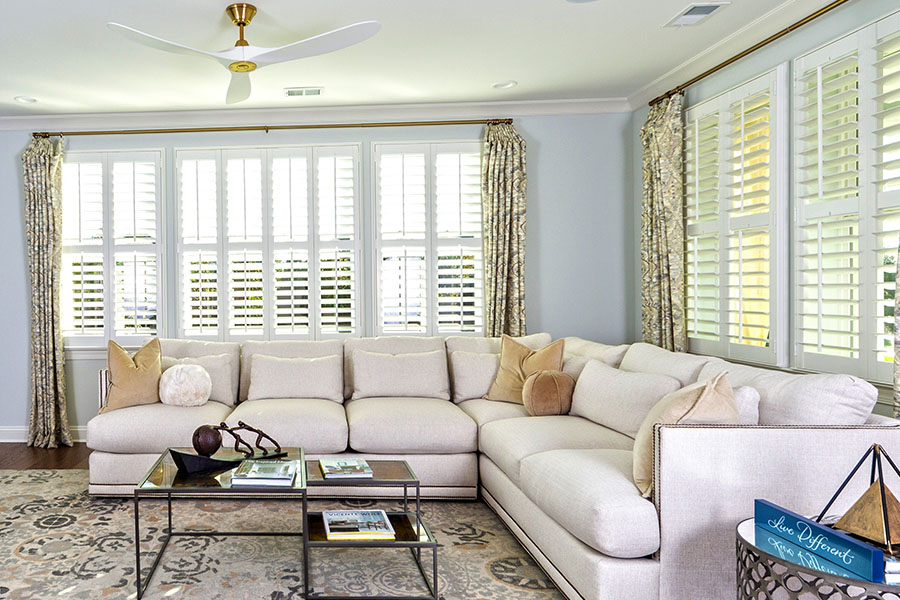 Corner of a living room with white polywood shutters.