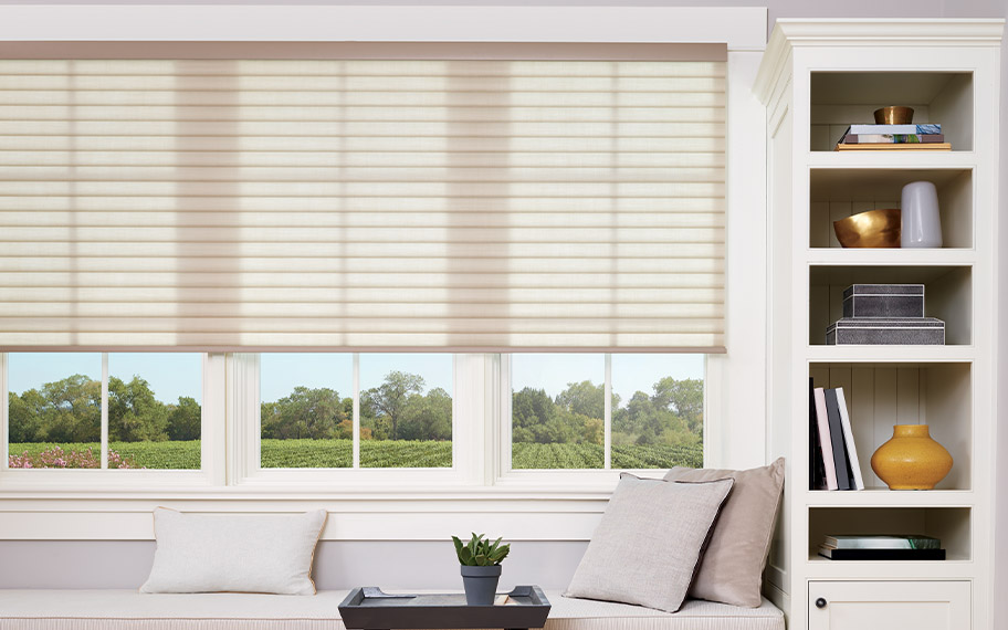 Beige cellular shades above a window seat