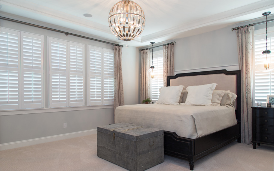 The right window treatments make any guest room a serene destination. White shutters in a bedroom.