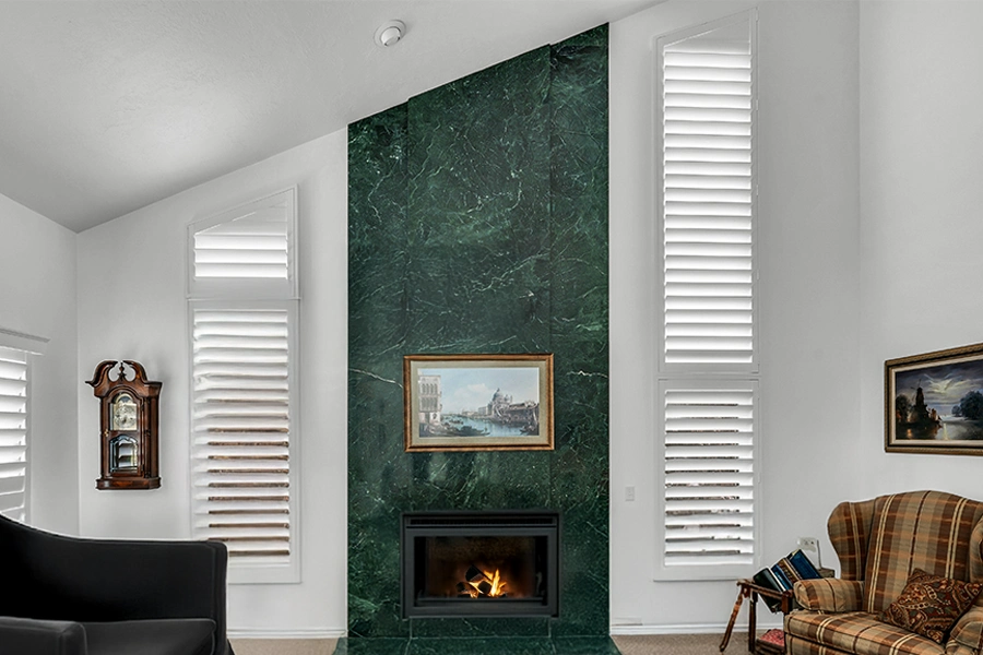 White Polywood shutters on angled windows on each side of a living room fireplace