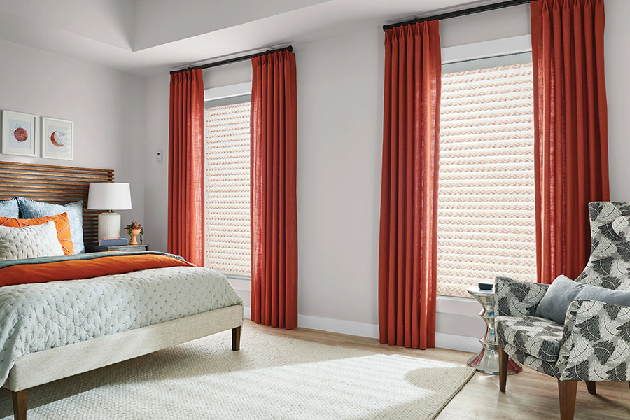 Choose your favorite window shade style and get it motorized for the ultimate combination of style and convenience! Orange and white patterned cellular shades on bedroom windows