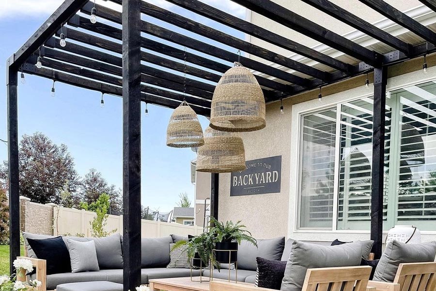 Stylish patio with string lights and other natural-styled light fixtures under a pergola.