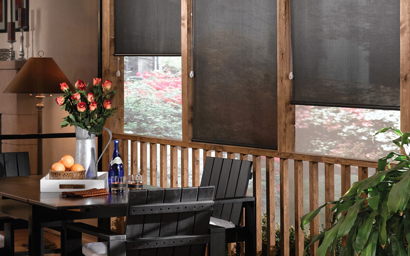 Wooden type of dining room with black roller shades.