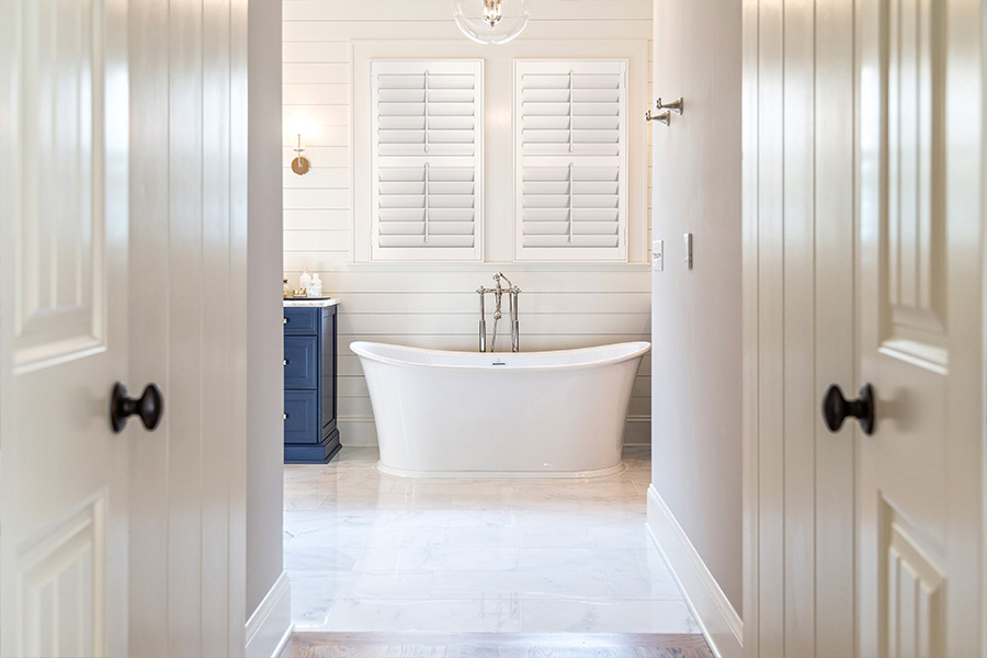 White Polywood shutters on windows over a white bathtub