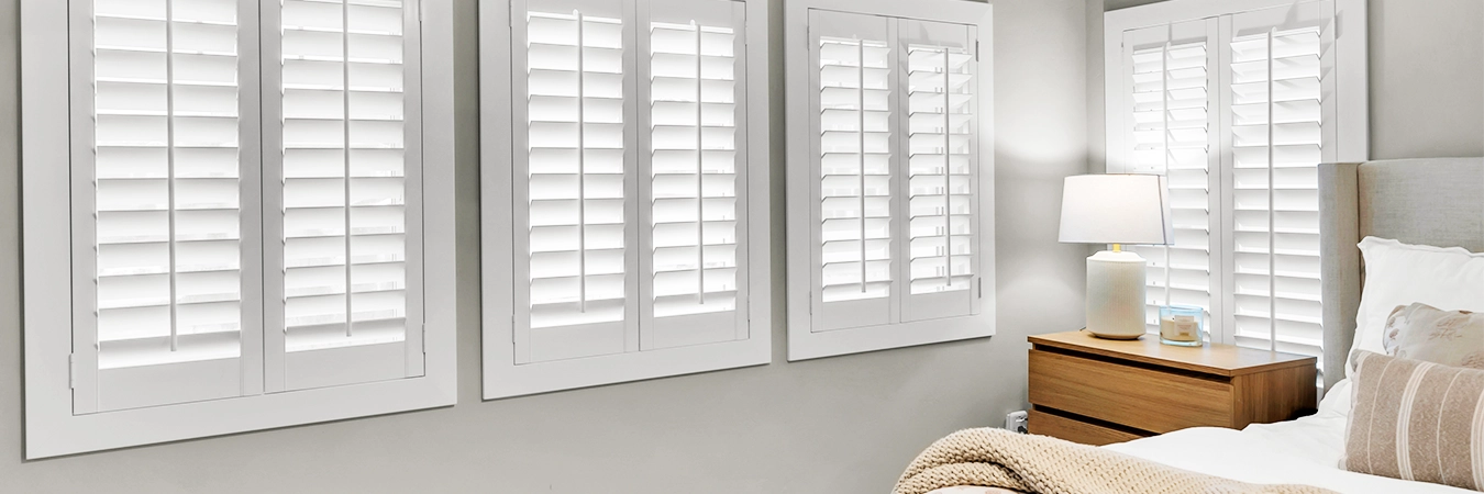 White Polywood shutters on windows in a white bedroom