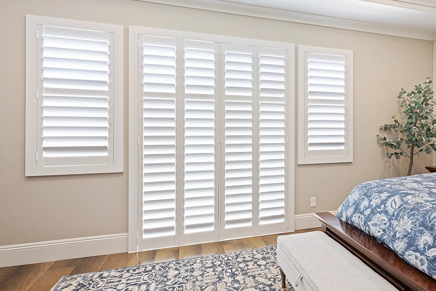 You won't find a paint that matches your Polywood shutter's incredible durability. White Polywood shutters on windows in a blue and white bedroom