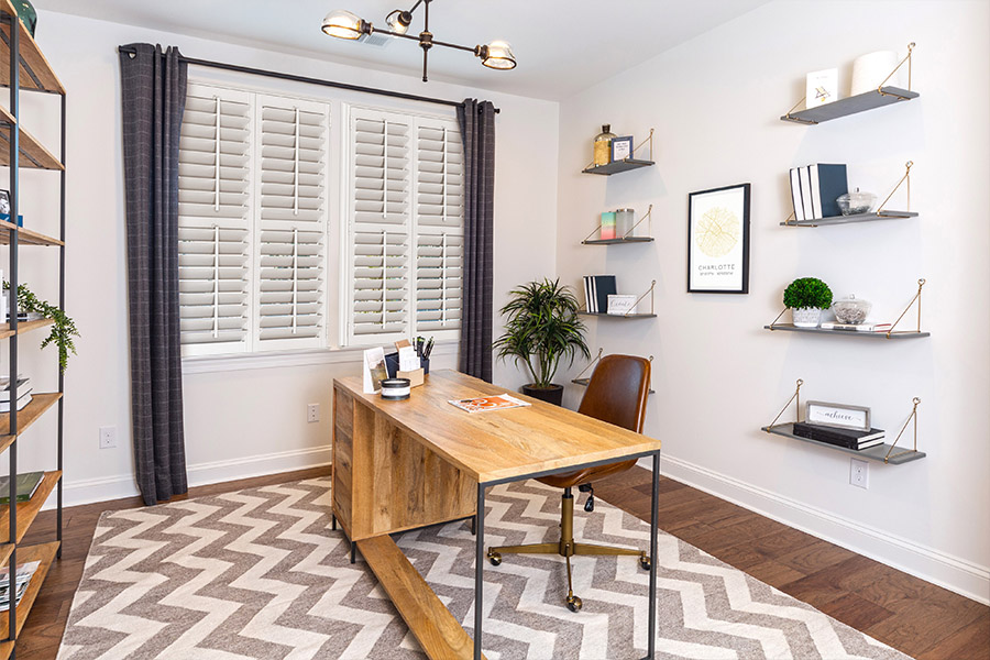 Polywood shutters let you block noise and distractions outside so you can concentrate in your home office. White Polywood shutters on a large home office window