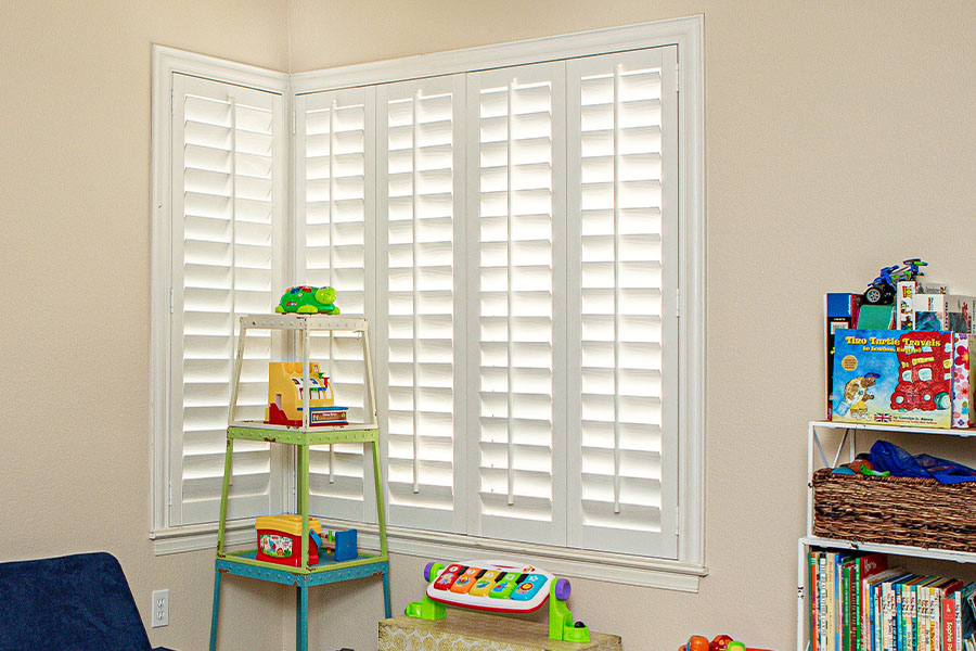 Polywood shutters on a window surrounded by toys in a children's playroom.