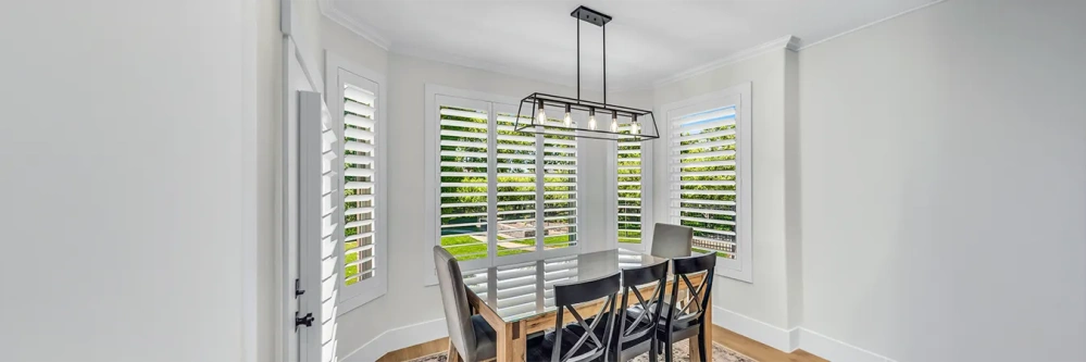 White plantation shutters in a bright, modern dining area