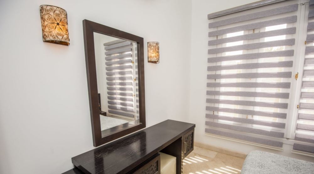 Zebra shades have the ability to filter light for enhanced privacy. Zebra shades next to a bedroom dresser.