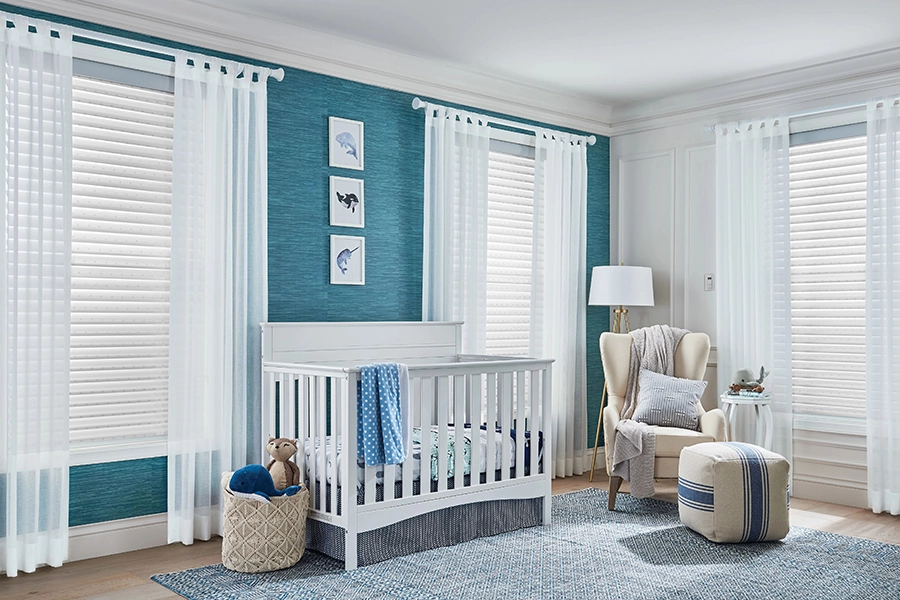 Light-weight curtains add a decorative touch to windows. Sheer white curtains on windows in a blue baby nursery