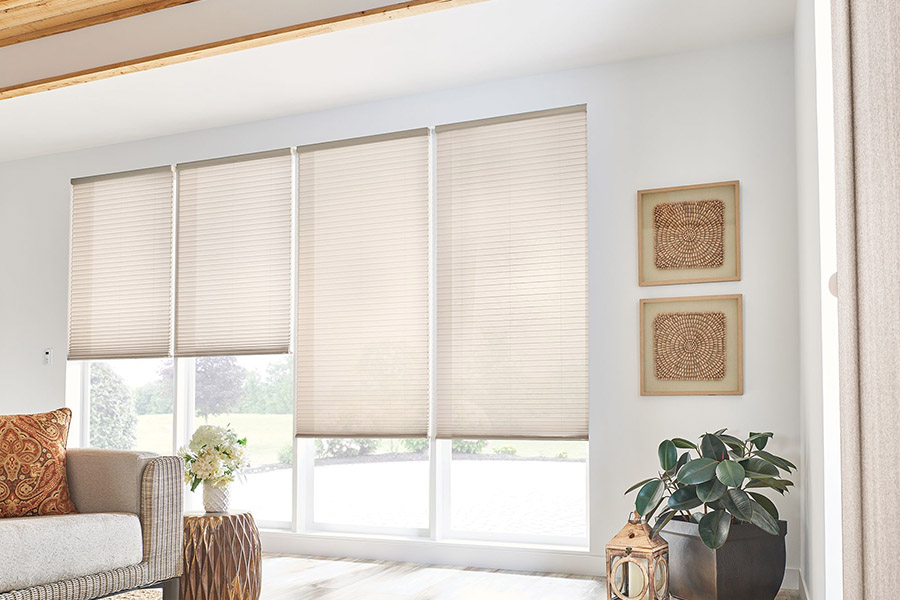 Big windows let in lots of summer heat. Cover yours with easy to use automatic window shades. Beige cellular shades on tall living room windows