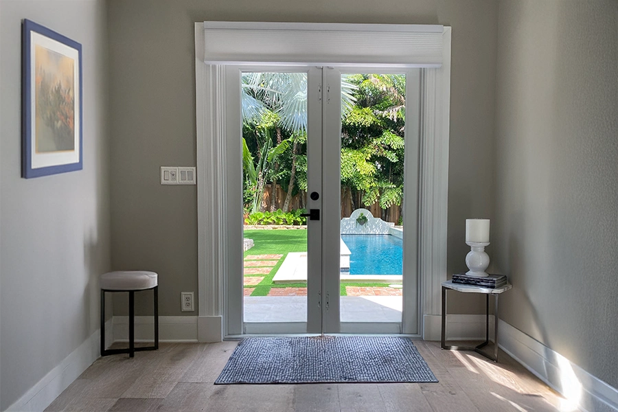 Cellular shades are a nice choice for French doors due to their energy efficiency and light control. They can be easily raised to provide a clear view outside. Cellular shades raised to the top of French doors leading to a backyard