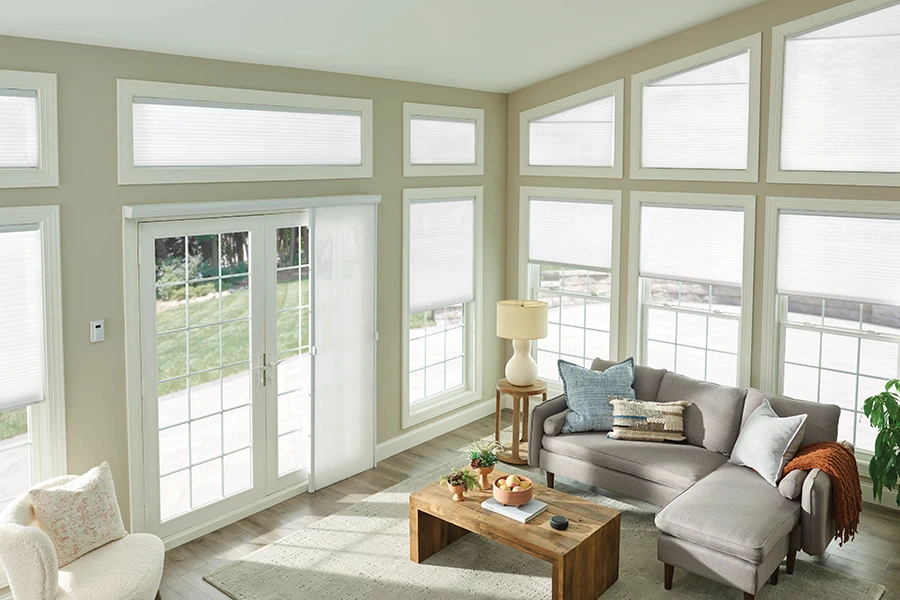 White cellular shades on a rake window in a beige living room