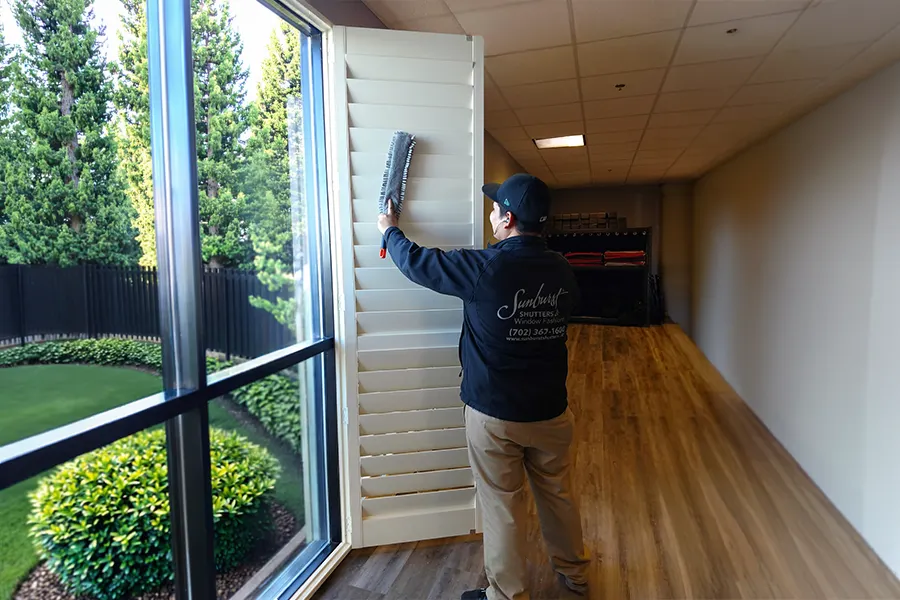 Sunburst Shutters employee cleaning a large Polywood shutter in the showroom