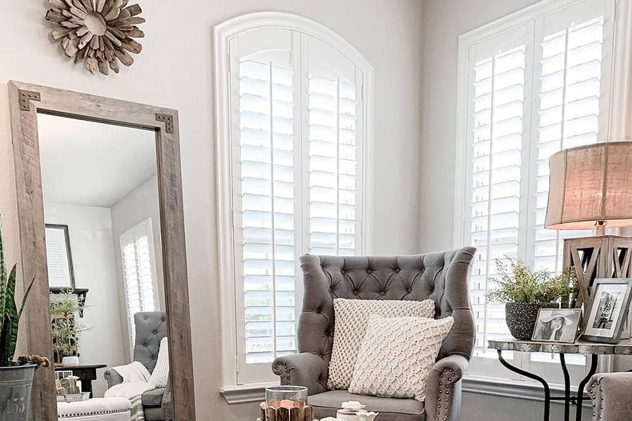 Create cozy corners in your home with cold-stopping Polywood shutters. Polywood shutters on corner windows in an elegant living room