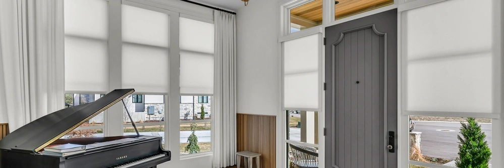 White window shades and drapes on windows in a room with a piano