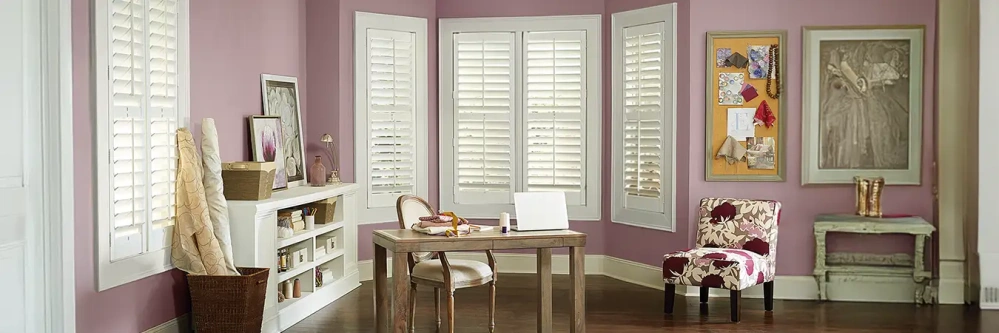 White Polywood shutters on bay windows inside of a sewing and craft room
