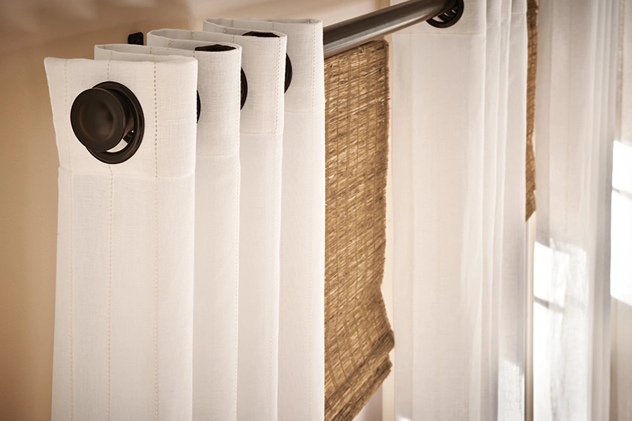 The right pleat style and material make drapes look modern. A close up view of white drapes hung from a rod with metal grommets