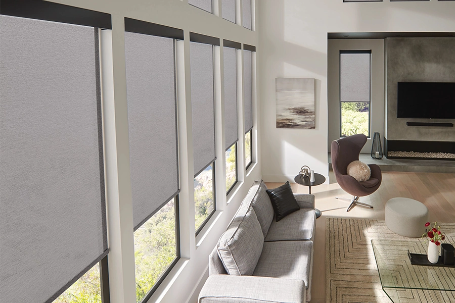 Easily control light and comfort levels with motorized shades on large, living room windows. Light-filtering motorized shades on large windows in an elegant living room