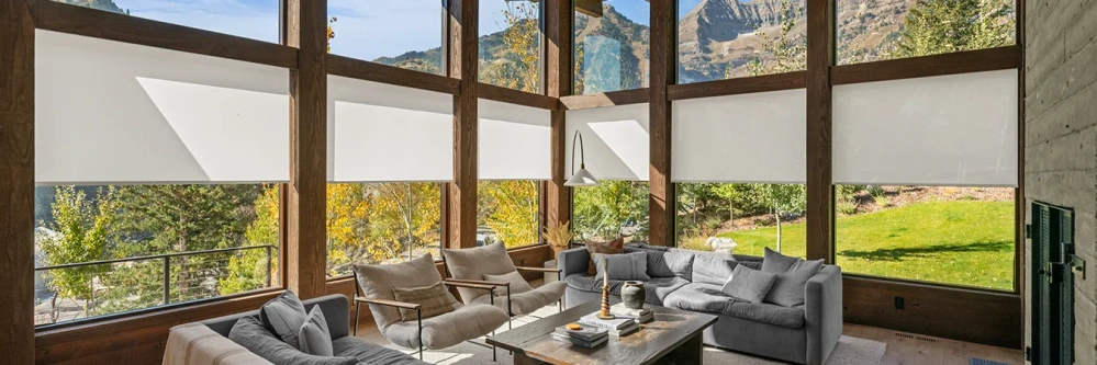 Motorized white window shades covering lower windows in a large space with exposed wood beams.