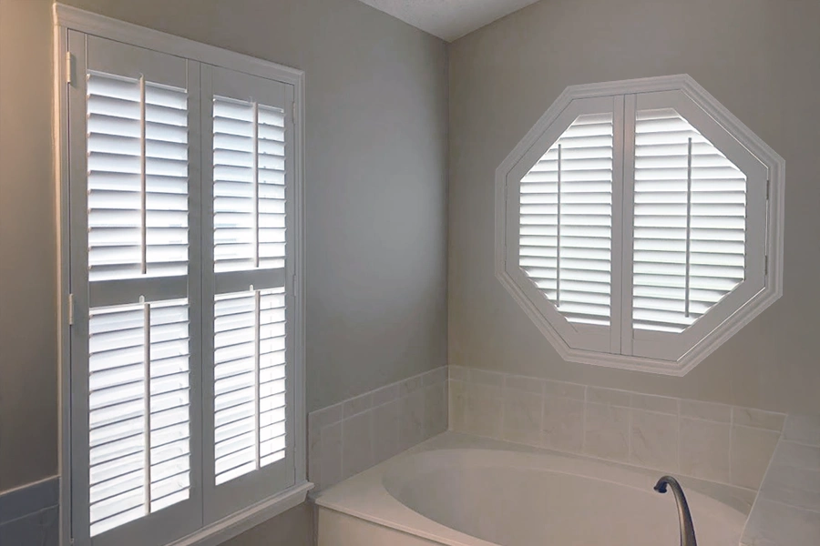 Easy to clean Polywood shutters make cleaning hexagon windows a breeze. Polywood shutters on a hexagon window in a bathroom
