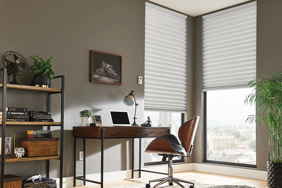 Control light and comfort levels in your home office with motorized cellular shades. White cellular shades covering windows in a home office
