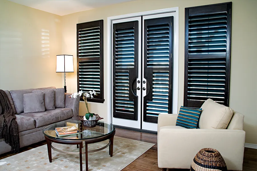 Ovation wood shutters in a dark finish on French doors and windows in a living room